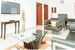 ein Wohnzimmer mit einem Glastisch und einem TV in der Unterkunft Lovely 2-bedroom house near Aburi in Accra