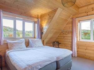 Bett in einem Holzzimmer mit zwei Fenstern in der Unterkunft Huize Tessel in Slenaken