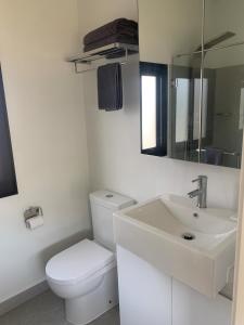 a white bathroom with a toilet and a sink at Yandina Caravan Park in Yandina