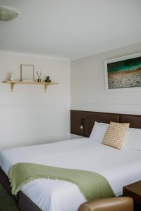 a bedroom with a white bed with a green blanket at PanCo Victor Harbor in Victor Harbor