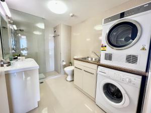 a bathroom with a washing machine and a sink at Seacrest, Surfers Beach Front 15A in Gold Coast