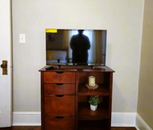 a man is reflected in the mirror of a tv on a dresser at Charming! near CLE Clinic/UH/CWRU/Dwntwn w/porch in Cleveland