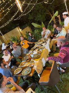 Un groupe de personnes assises autour d'une longue table avec de la nourriture dans l'établissement Emerald Villa, à Kigali