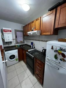 eine Küche mit weißem Kühlschrank und Holzschränken in der Unterkunft ALQUILO DEPTO AMUEBLADO 2 DORMITORIOS EN MICROCENTRO in Río Cuarto