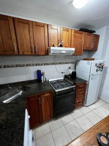 eine Küche mit Holzschränken, einem Herd und einem Kühlschrank in der Unterkunft ALQUILO DEPTO AMUEBLADO 2 DORMITORIOS EN MICROCENTRO in Río Cuarto + 1 Foto