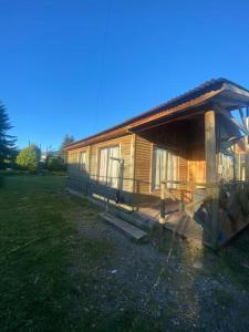 a wooden cabin with a porch on a grass field at Cabaña en sector residencial in Puerto Aisén