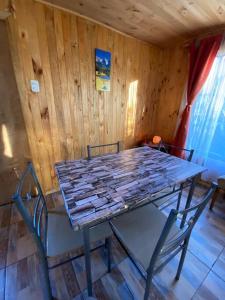stół i krzesła w pokoju z drewnianymi ścianami w obiekcie Cabaña en sector residencial w mieście Puerto Aisén