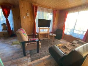 sala de estar con sofá y TV en Cabaña en sector residencial, en Puerto Aysén