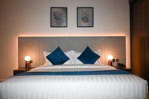 um quarto com uma grande cama branca com almofadas azuis em فندق سافوي جدة Savoye Hotel em Jeddah