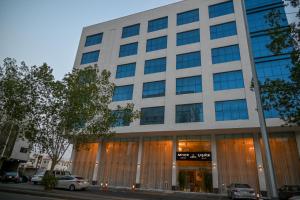 un grande edificio bianco con finestre in vetro di فندق سافوي جدة Savoye Hotel a Gedda