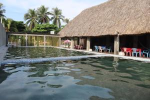 a house with a swimming pool with a thatch roof at El Pacific Surf House in Sipacate