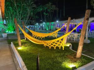 a yellow hammock sitting on the grass at night at Pousada Puerta Del Sol Rio das Ostras in Rio das Ostras