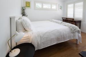 a white bedroom with a white bed and a lamp at Seymour Sleeps in Nelson