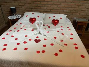 una cama con corazones rojos en las sábanas en Pousada Vista Bonita, en Visconde De Maua