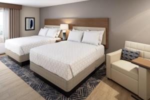 um quarto de hotel com duas camas e uma cadeira em Candlewood Suites - Roanoke Airport em Roanoke
