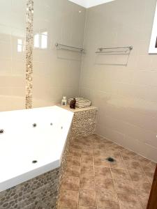 a bathroom with a large tub and a tile floor at Hannah's Place in the heart of Lovedale, Hunter Valley wine country, Free bottle of wine with each booking in Lovedale