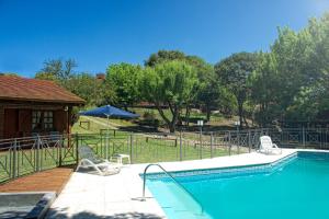 a swimming pool with two chairs and an umbrella at Cabañas del Golf in La Cumbre