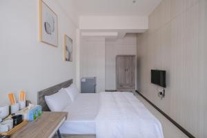 una camera con un grande letto bianco e una TV di Yang a Yujing