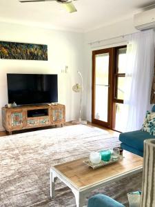 a living room with a tv and a couch and a table at Hannah's Place in the heart of Lovedale, Hunter Valley wine country, Free bottle of wine with each booking in Lovedale