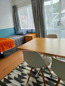 a room with a table and chairs and a bed at Aarangi Tui Motel in Paihia