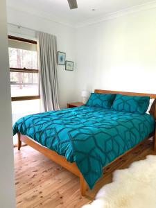 1 dormitorio con 1 cama con edredón azul en Hannah's Place in the heart of Lovedale, Hunter Valley wine country, Free bottle of wine with each booking, en Lovedale