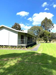 a white building with a grass field next to it at Hannah's Place in the heart of Lovedale, Hunter Valley wine country, Free bottle of wine with each booking in Lovedale