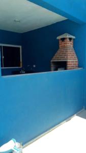 um quarto azul com uma lareira de tijolos na parede em Casa temporada em peruibe em Peruíbe