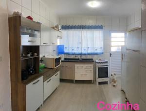uma cozinha com electrodomésticos brancos e uma grande janela em Casa temporada em peruibe em Peruíbe