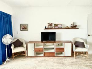 a living room with a television and two chairs at Beach & Ocean Front Apartments Brisas Cancun Zona Hotelera in Cancún