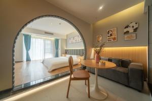 a bedroom with a bed and a table and a couch at AT NIGHT HOTEL Chengdu in Chengdu