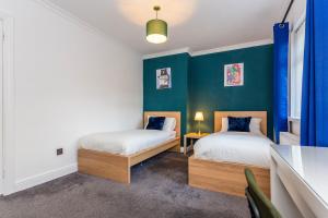 two beds in a room with blue walls at Millway Apartments Newcastle Gateshead with Free Parking in Sheriff Hill