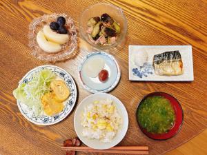 een tafel met borden en schalen van voedsel bij Guest House Island in Wakamatsu