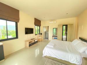 een slaapkamer met een wit bed en een televisie bij Cozy Apartment Chaweng Center in Chaweng Beach