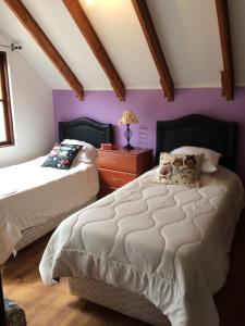 1 dormitorio con 2 camas y paredes moradas en Casa Paihuen, en Catapilco