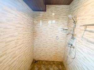 uma casa de banho com um chuveiro numa parede de tijolos em Jero Delod Kedungu em Tabanan