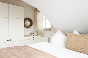 a white bedroom with a bed and a mirror at Oewern Diek App 13 in Wustrow