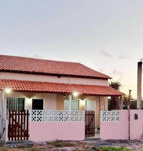 une petite maison avec une clôture blanche devant elle dans l'établissement Casa em Pratigi, Universo Paralelo, Ituberá Ba., à Pratigi