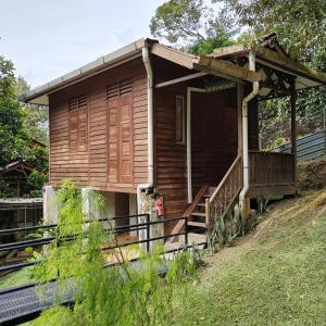 uma pequena casa de madeira numa colina com um alpendre em D'Bukit Forest em Pedas