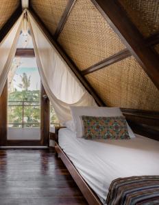 Bett in einem Zelt mit einem Kissen und einem Fenster in der Unterkunft Harana Surf Resort in General Luna