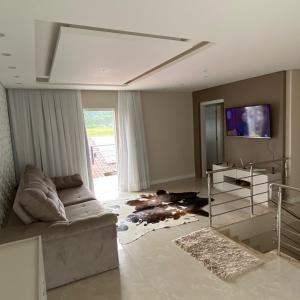 a living room with a couch and a tv at Gih Guest House Parque Beto Carrero in Penha