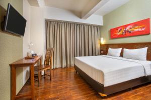 a bedroom with a bed and a desk and a television at 1O1 URBAN Jakarta Thamrin in Jakarta