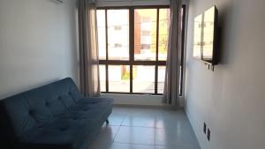 a living room with a couch and a large window at Apartamento no NDM Bessa in João Pessoa