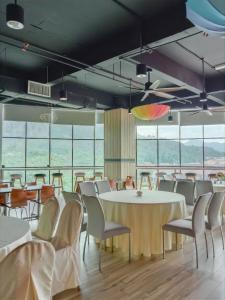 a dining room with tables and chairs and windows at Langkasuka Express in Kuah