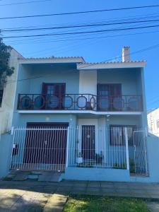 uma casa branca com uma cerca e uma varanda em Quarto em Casa na rua mais linda da Cidade em Rio Grande