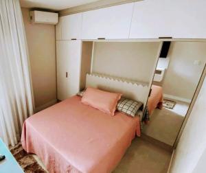 a small bedroom with a pink bed and a mirror at Gih Guest House Parque Beto Carrero in Penha