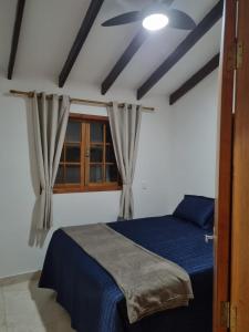 a bedroom with a blue bed and a window at Sítio Quinta da Mata Chalé Amarelo in Pirenópolis