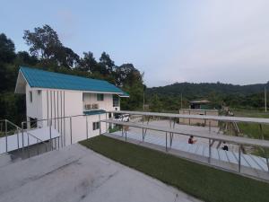 a white building with a blue roof next to a field at ที่พักนครนายกโฮมสเตย์Ckhouse in Ban Khao Nam Sap (1)