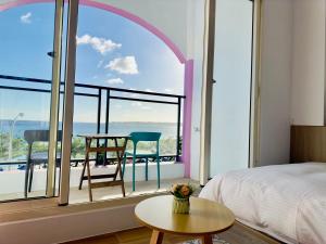 a bedroom with a bed and a table and a large window at 南灣陽光皮小妞 Pii hostel in Nanwan