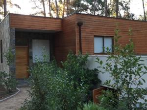 ein kleines Haus mit Holzfassade und Bäumen in der Unterkunft House & Lake rapel in Las Cabras