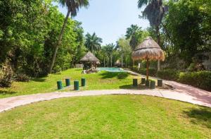 a resort with a pool and a straw umbrella at Private Room Puerto Morelos in Puerto Morelos